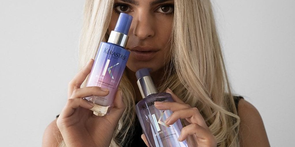 A person holding two bottles of Kérastase haircare products.