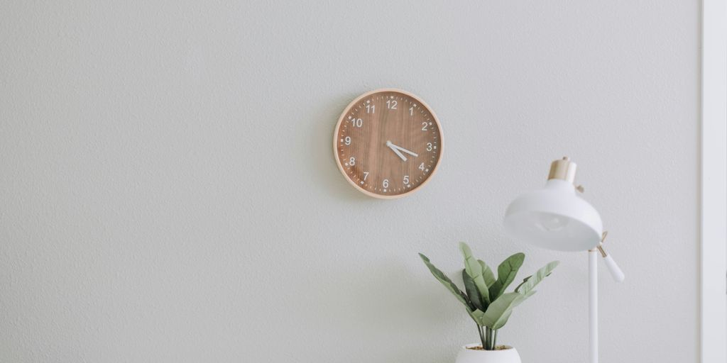 Wall clock and potted plant in a home office setting, emphasizing a clean and professional background for virtual meetings.