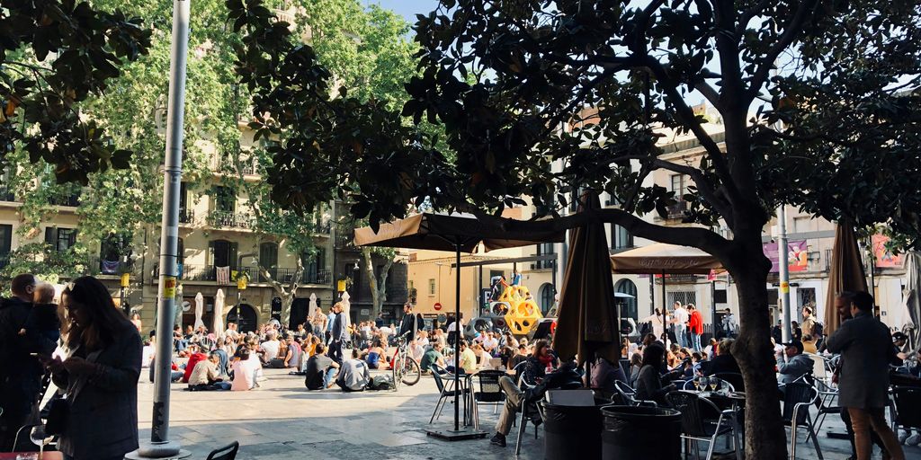 people sitting beside buildings and trees during daytime