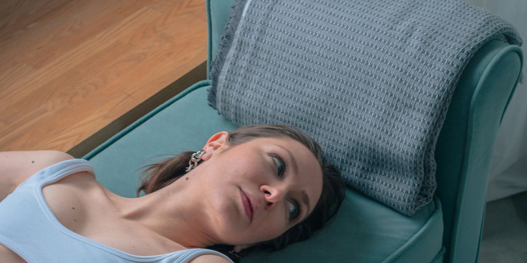 a woman laying on a couch with a pillow