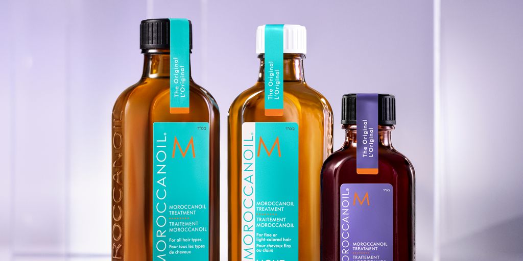 Four bottles of hair treatment products on a reflective surface.