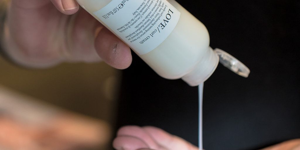 Person dispensing lotion from bottle into hand, skincare product demonstration.