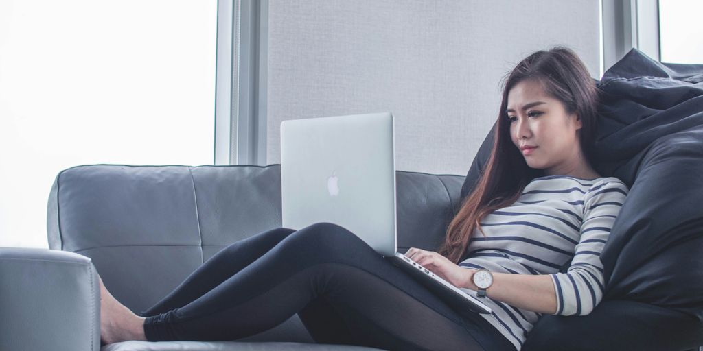 woman sitting on sofa while using MacBook Pro