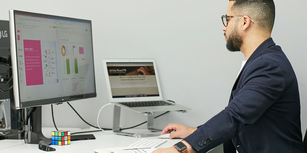a man sitting at a desk with a laptop and a computer