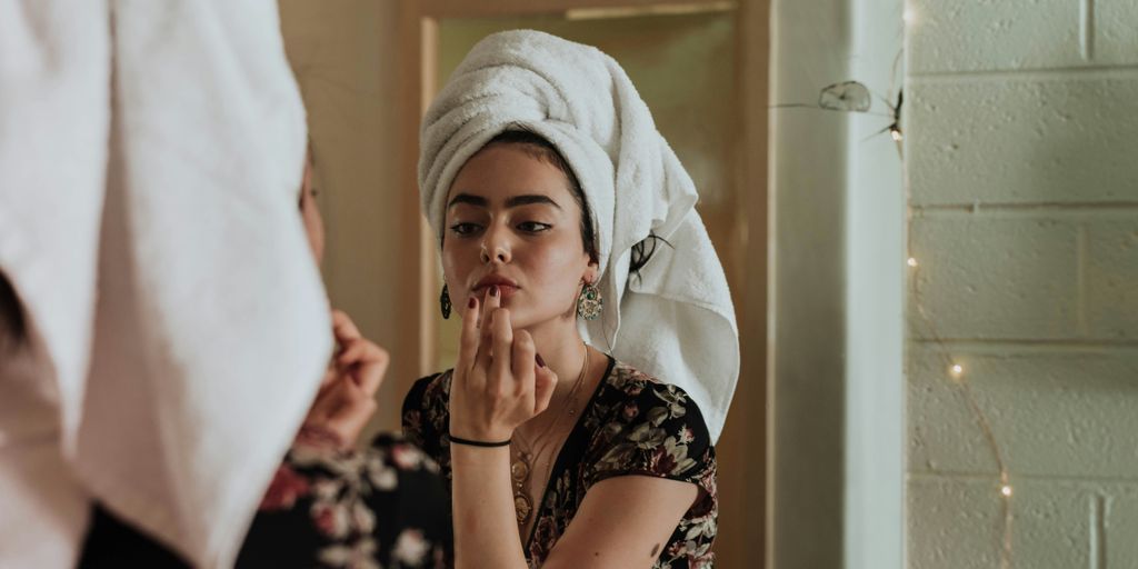 woman putting makeup in front of mirror