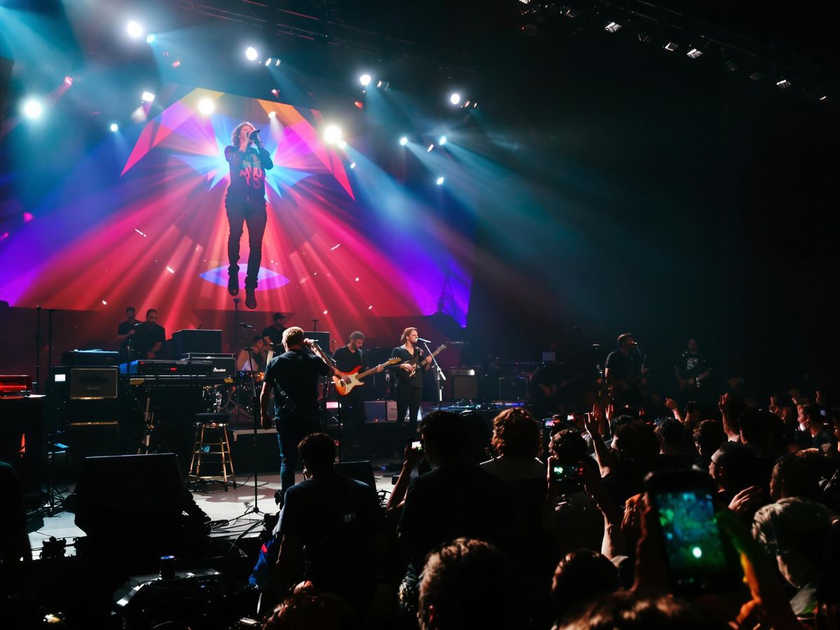 Musicians performing on stage with energetic crowd.