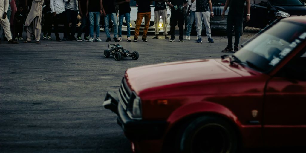 a group of people standing around a red car
