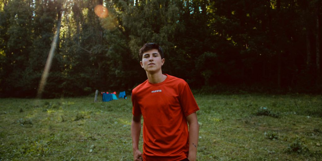 boy in red crew neck t-shirt standing on green grass field during daytime
