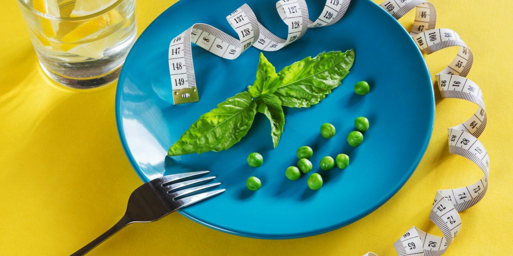 a blue plate topped with green vegetables and measuring tape