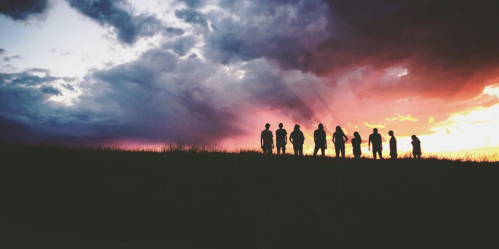 silhouette of nine persons standing on the hill