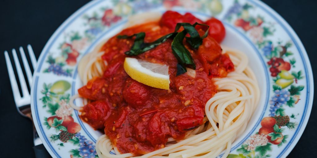 Spaghetti with tomato sauce and lemon on a plate.