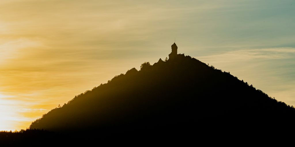 a silhouette of a hill with a clock tower on top