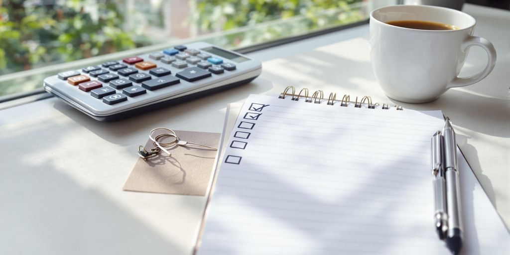 Workspace with notepad, calculator, and coffee for bookkeeping.