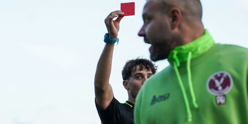 A man in a green hoodie holding up a red card