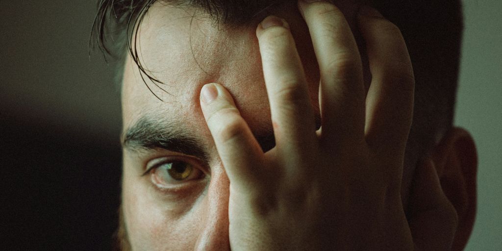 man covering his face with his hand