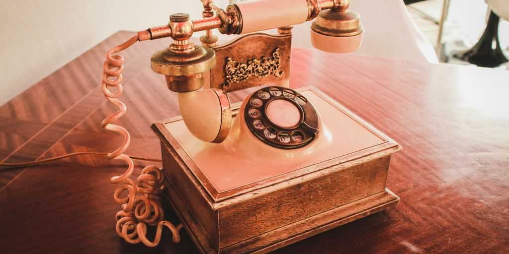 white and brown rotary telephone on brown wooden table