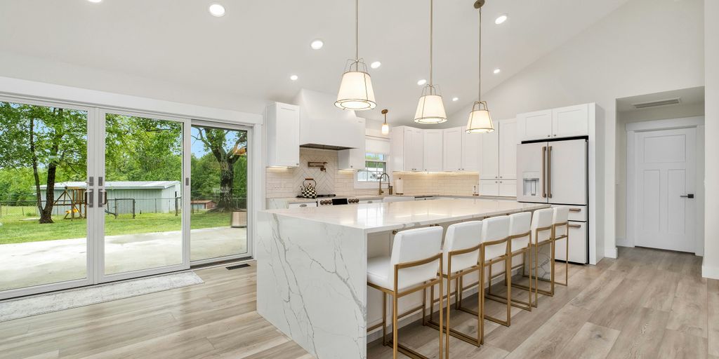 a large kitchen with a center island and marble counter tops
