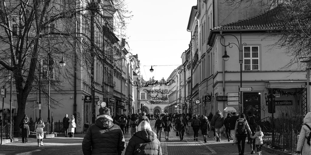 A group of people walking down a street next to tall buildings