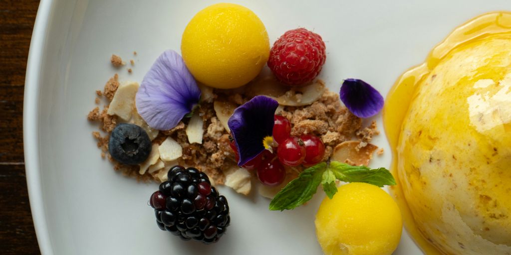 a white plate topped with fruit and a scoop of ice cream