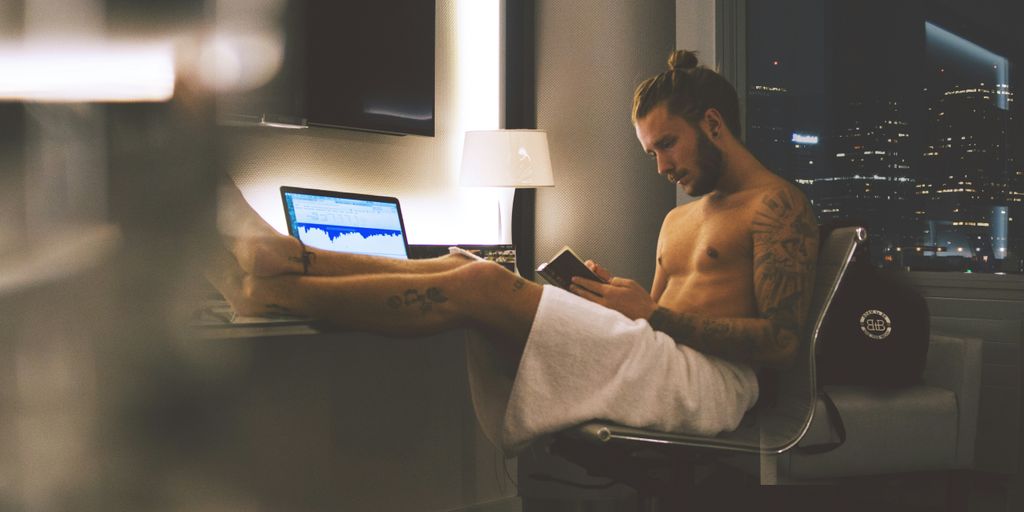 man sitting on rolling chair while using smartphone