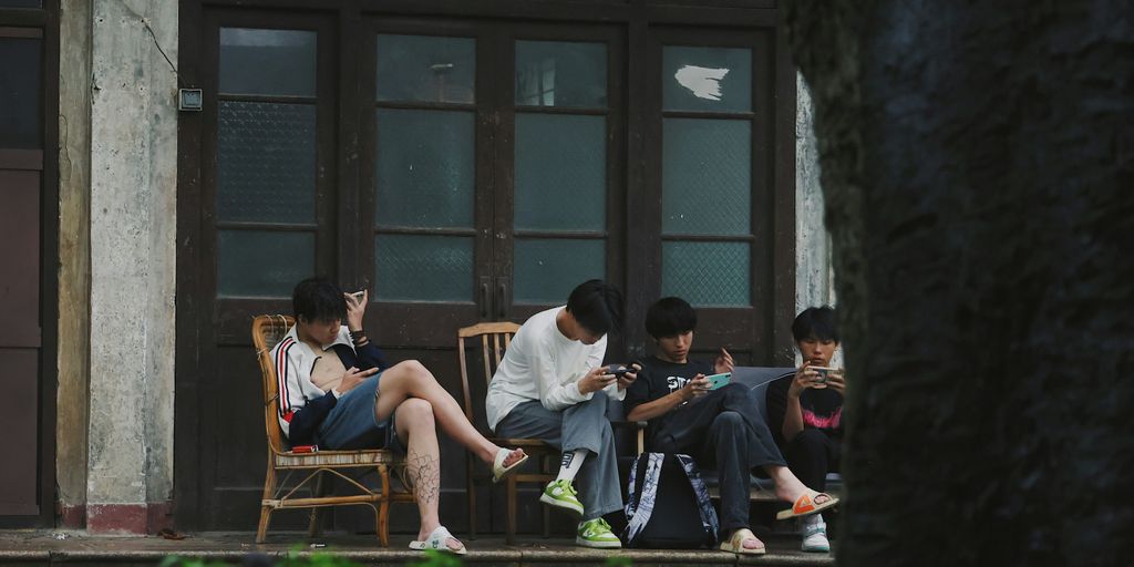 A group of people sitting on a porch next to a tree