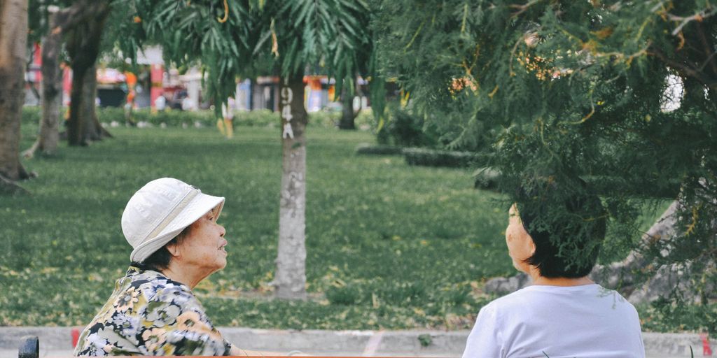 man in white hat sitting on bench during daytime