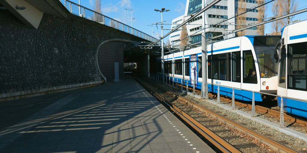 a blue and white train traveling under a bridge