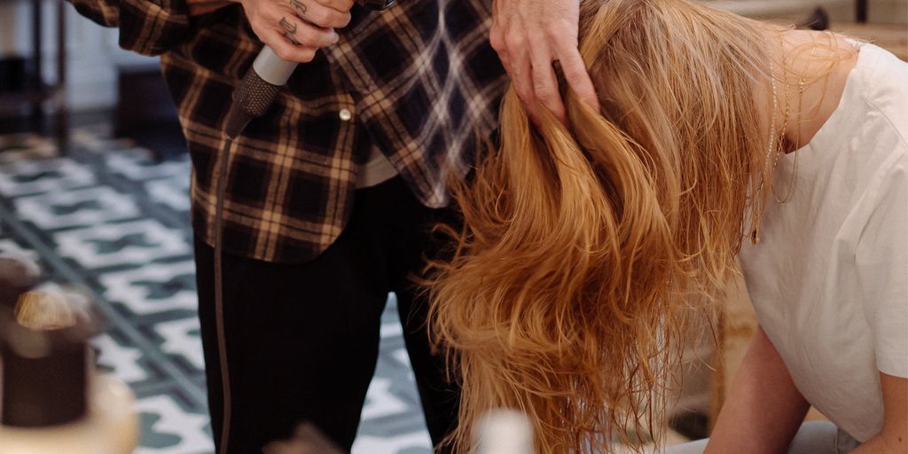 Person styling another person's hair in a salon environment.