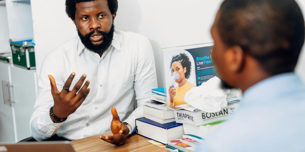A man sitting at a desk talking to another man