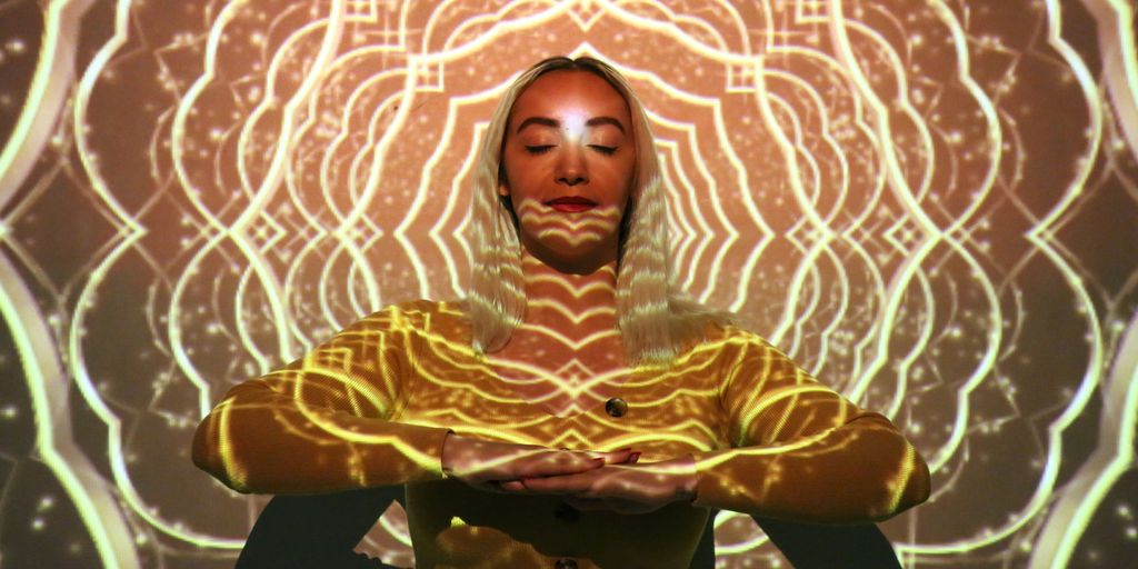 a woman in a yellow outfit is standing in front of a glowing background