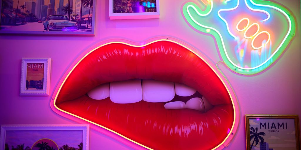 A wall with a neon sign and a red lip