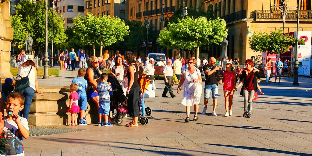 A crowd of people walking down a street next to tall buildings