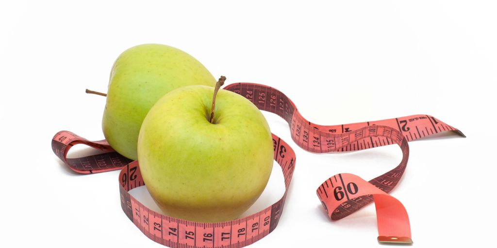 two green apples with a measuring tape around them