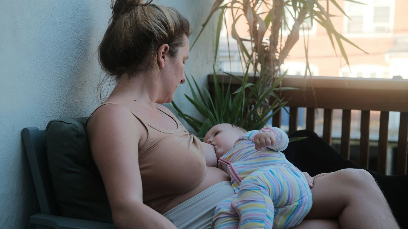 a woman sitting on a bench holding a baby