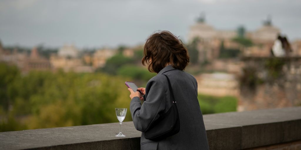 A woman standing on a bridge looking at her cell phone