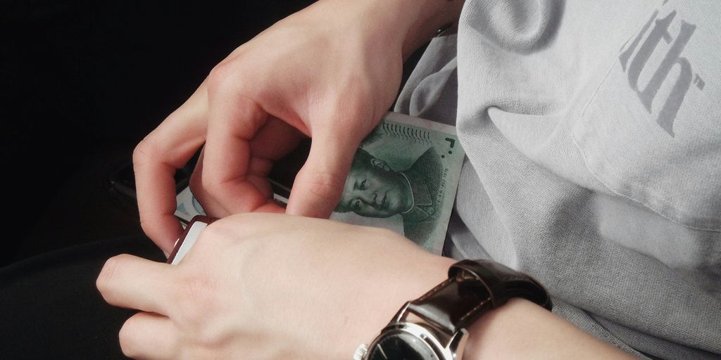 A person holding a watch and a money in their hand