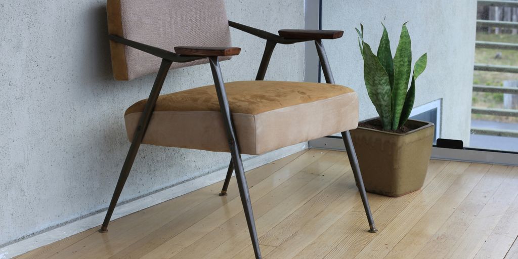 brown fabric padded armchair beside green snake plant inside room