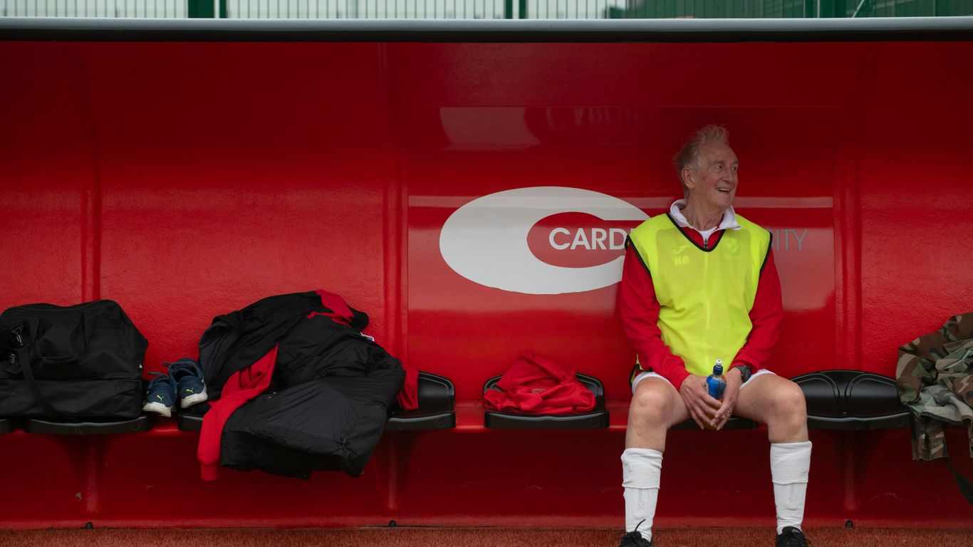 A man sitting on a bench in front of a red wall