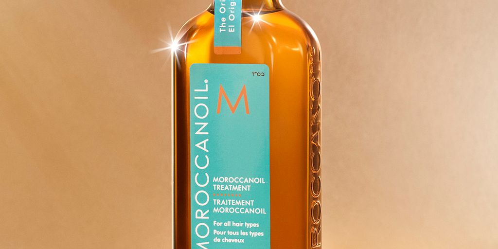 Bottle of Moroccanoil hair treatment on a reflective amber surface.
