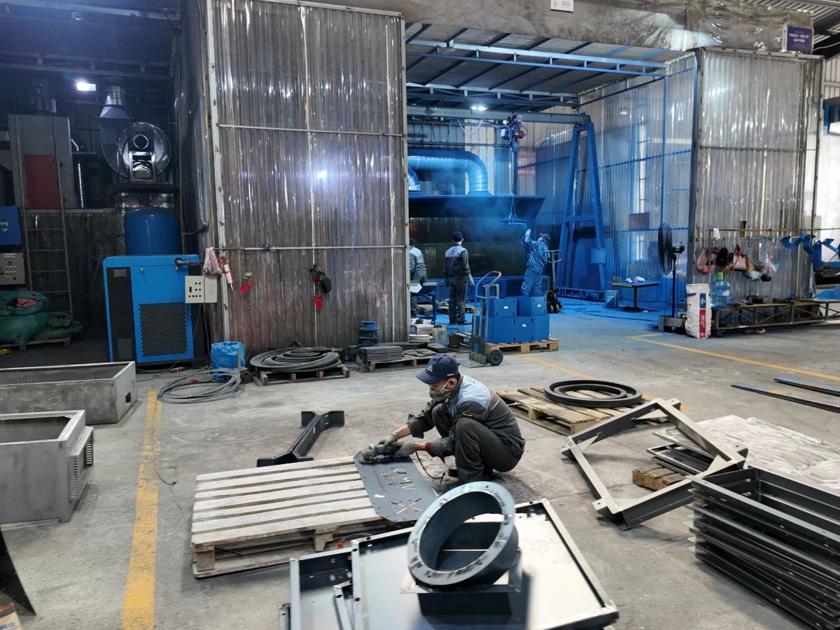 Industrial workspace with machinery, tools, and metal components visible.