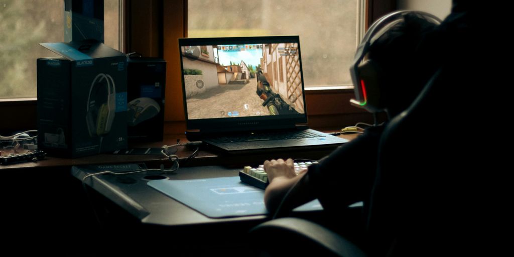 A gamer plays a video game on their laptop.
