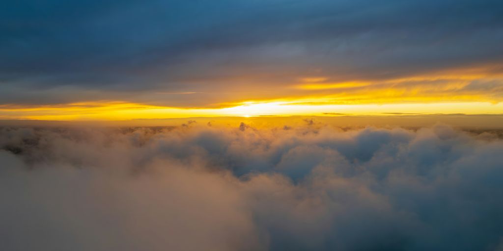 the sun is setting over the clouds in the sky