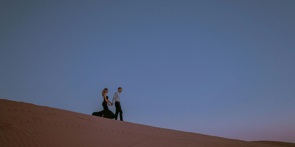 man and woman standing on brown sand under blue sky during daytime