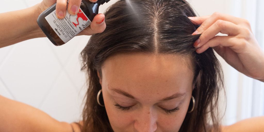 Applying hair treatment product, self-care routine, indoors, close-up view.