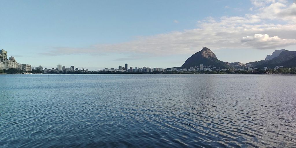 body of water near mountain under blue sky during daytime