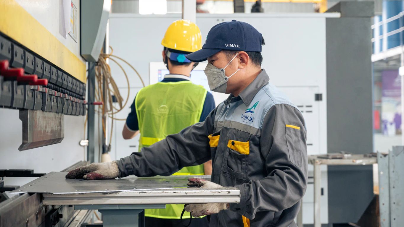 Two workers operating machinery in an industrial setting.