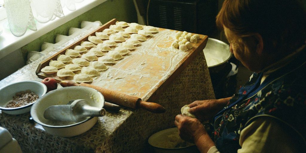 a woman in a kitchen making dough on a table