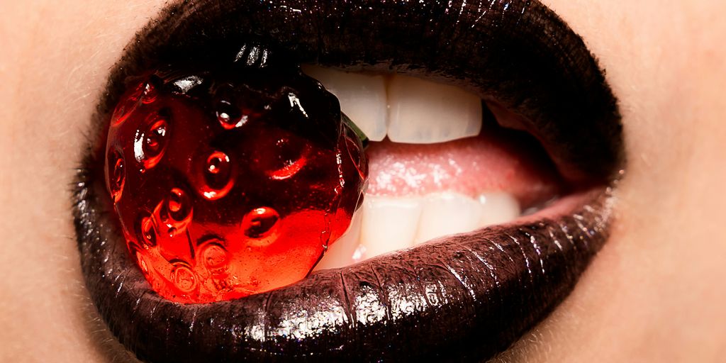 woman biting red strawberry candy
