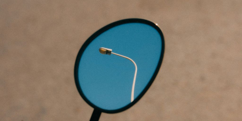 a close up of a mirror with a street light in the reflection