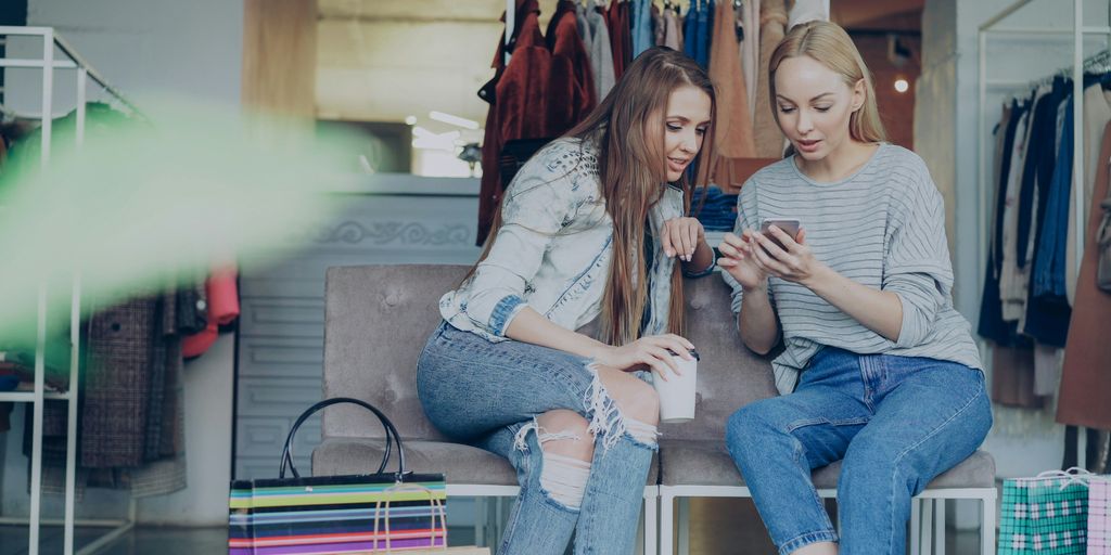 Two women are looking at a phone in a store.